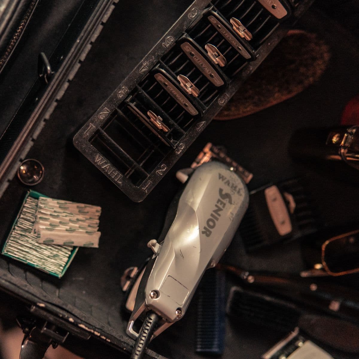 La mesa de trabajo de una barbería con máquinas, cuchillas y peines.