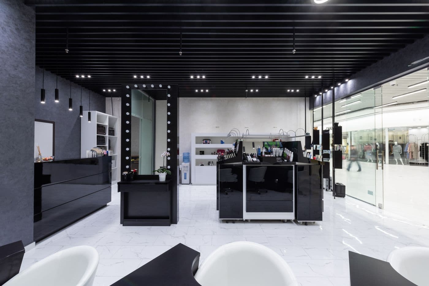 La recepción de un centro de estética moderno, en blanco y negro, con los tocadores al fondo.